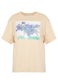 Beige bomullströja med en avslappnad passform, och med ett blommönster av blå iris i en vas samt gröna accenter på trycket.