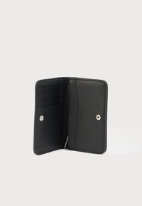 Μαύρο δερμάτινο πορτοφόλι με ομαλή υφή, που διαθέτει πολλαπλές θήκες για κάρτες και μια τσέπη με φερμουάρ, ασφαλισμένο με ασημένιο κούμπωμα.