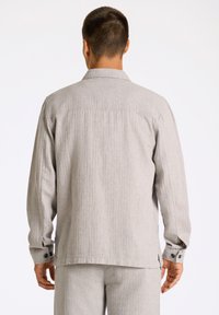 Grå, randig långärmad skjorta med krage, knappade ärmslut och rak nederkant. Lättviktsmaterial med en diskret struktur.