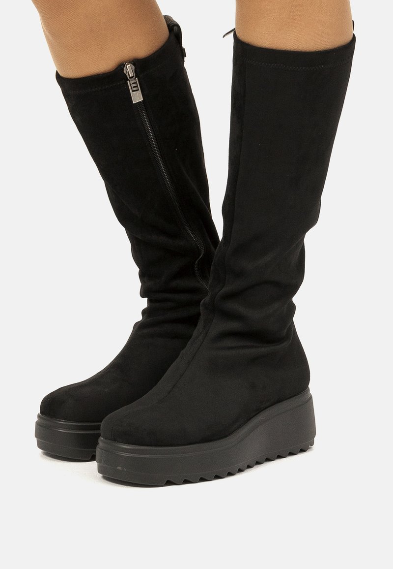 Bottes noires montantes en suède doux avec une épaisse semelle plateforme et un détail de fermeture éclair sur le côté. Texture lisse et design décontracté.