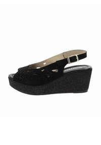 Sandale à talon compensé noir avec dessus en suède perforé, bout ouvert, réglage de la sangle de cheville et plateforme texturée.