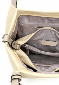 Licht beige handtas met een gladde buitenkant en een gevoerde binnenkant. Voorzien van meerdere ritsvakken en een subtiel logopatroon.