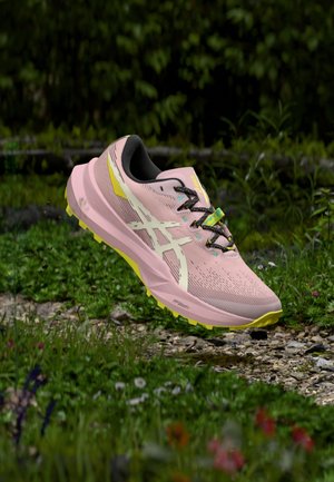 Sapatilha de corrida rosa claro com parte superior em malha texturizada, acolchoamento preto, detalhes amarelos e atacadores multicoloridos; projetada para uso ao ar livre.