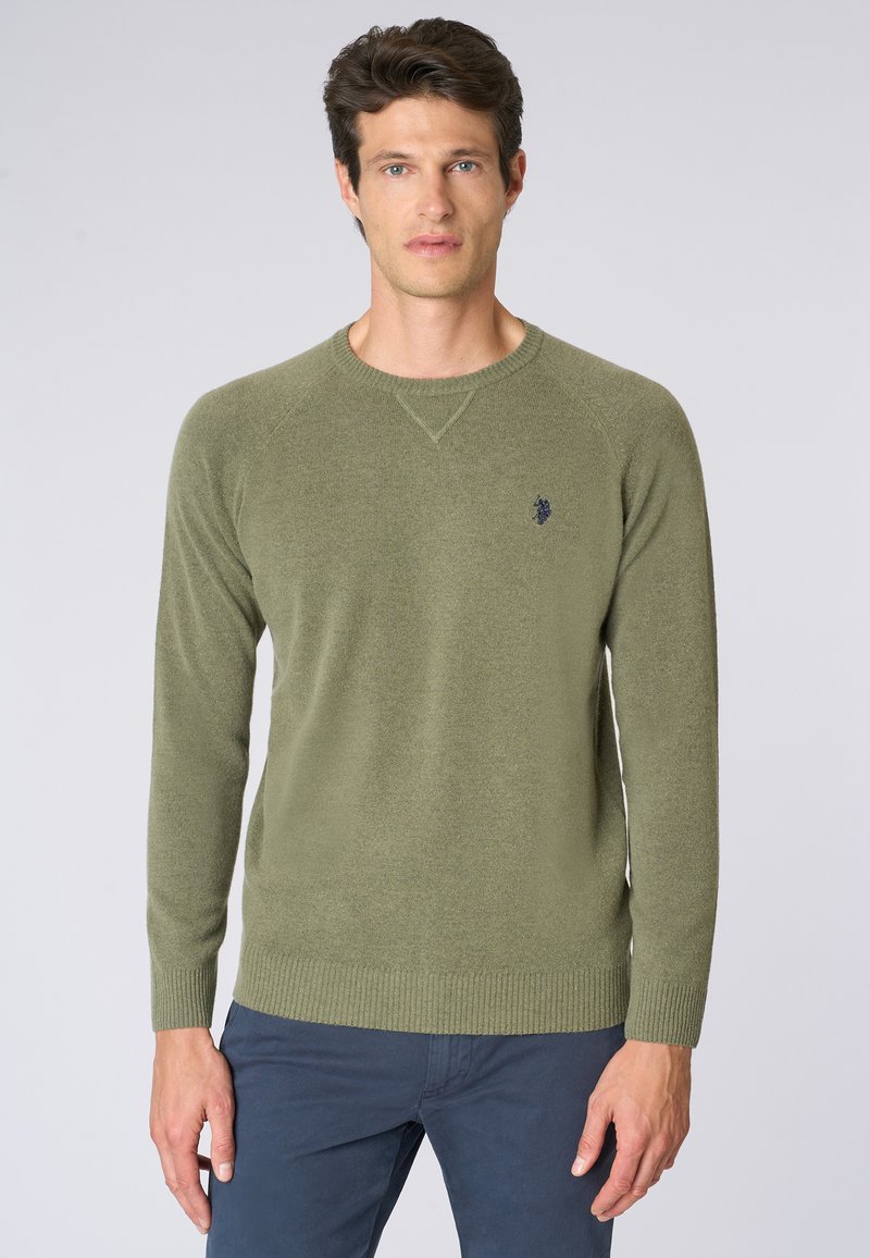 Maglione lavorato a maglia verde oliva con maniche lunghe, colletto a girocollo e polsini a coste. Presenta un piccolo logo navy sul petto. Tessuto morbido.