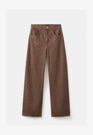 Braune High-Waist-Hosen mit weitem Bein und schwarzen Punkten, Vorder- taschen, Gürtelschlaufen und Knopfverschluss.