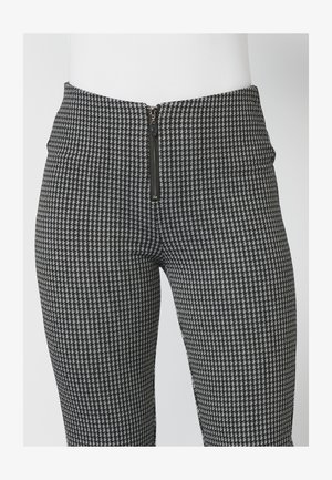 Leggings s črno-belim houndstooth vzorcem z gladko teksturo in zadrgo na pasu. Prilagojen silhueta z visokim pasom.
