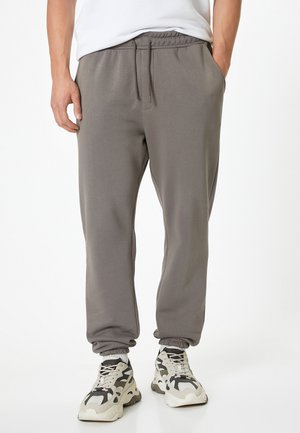 Grijze joggerbroek met een elastische tailleband, zijzakken en manchetankels, gemaakt van zachte stof, gecombineerd met chunky sneakers.