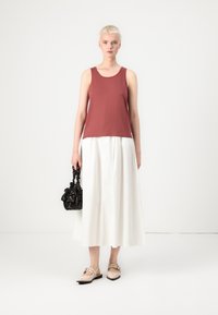 Hnědá tank top, bílá splývavá sukně, černá vzorovaná kabelka a světlé boty. Jednoduchý, neformální outfit s různými texturami.