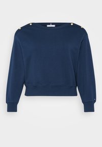 Marineblå cropped sweatshirt laget av bomull. Har gullfargede dekorative knapper på skuldrene og ribbestrikkede mansjetter og nederkant.