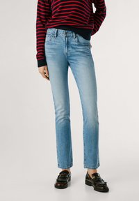 Heledad sinine denimist teksad sirge lõikega, keskmise tõusuga vöökohaga ja kerge tuhmumisega. Kombineeritud mustade mokassiinidega.