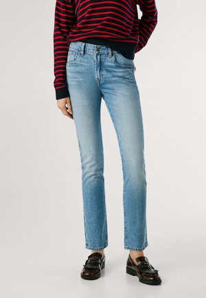 Jeans in denim blu chiaro con taglio dritto, caratterizzati da una vita media e una leggera scoloritura. Indossati con mocassini neri.
