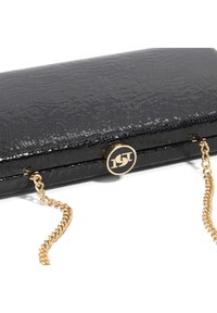 Black patent leather clutch with a textured surface, featuring a gold chain strap and circular gold hardware with a logo detail.