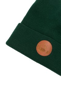 Zielona dziana czapka z podwiniętym brzegiem, z brązową skórzaną łatą wytłoczoną w inspirujące motywy przyrody. Gładka faktura.