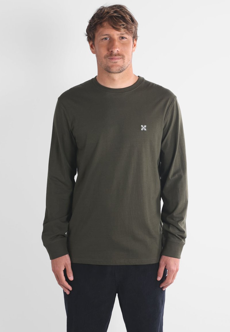 Chemise à manches longues en tissu coton olive, avec un petit logo blanc sur la poitrine gauche, un col rond et des manches ajustées.