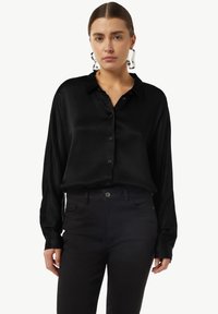 Black satin button-up shirt with long sleeves, collar, and subtle sheen, worn with black pants, displayed against a white background.