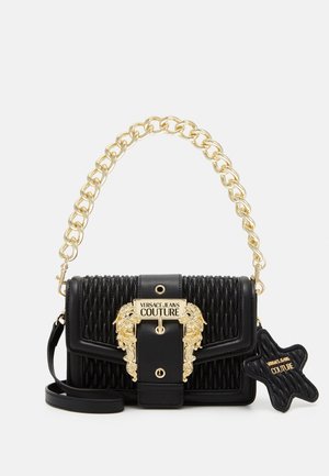 Czarna pikowana torebka na ramię z uchwytem w postaci złotego łańcuszka, ozdobną złotą klamrą z napisem „Versace Jeans Couture” oraz odpinanym breloczkiem w kształcie misia.