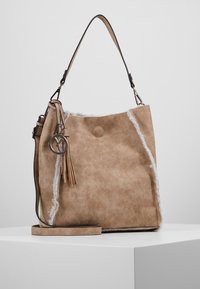 Brun ruskindshåndtaske med en frynset kvast, hvid pelskant og en aftagelig skulderrem. Har en cirkulær metalbeklædning som detalje.