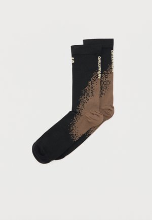 Par sokker til midt på leggen med svart til brun pikselert gradient og liten lys tekst langs siden på ensfarget bakgrunn.