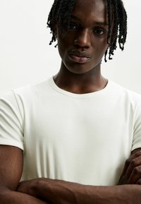 White ribbed t-shirt with a round neckline. The fabric appears soft and fitted, featuring short sleeves and an even texture.