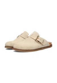 Mule in suede beige senza lacci con punta rotonda, dotato di una cinghia laterale e dettaglio con fibbia metallica, poggiato su una suola piatta marrone.