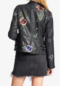 Czarna skórzana kurtka z kwiatowym haftem w kolorze czerwonym, niebieskim i zielonym. Charakteryzuje się dopasowanym krojem, bocznymi klamrami i gładką teksturą.