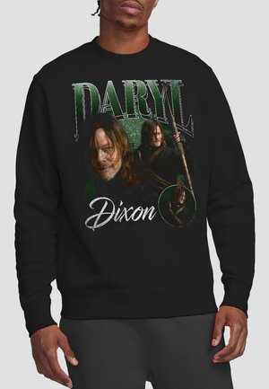 Man wearing black sweatshirt with three images of a long-haired man holding a staff and the text "Daryl Dixon" in green and white.