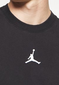 Felpa nera con logo "Jumpman" bianco sul petto, realizzata in morbido tessuto con colletto a girocollo a costine e vestibilità rilassata.