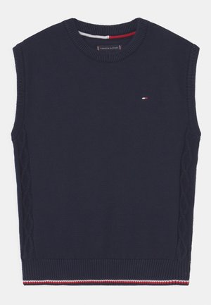 Un pull sans manches bleu marine avec un col rond côtelé, des accents en tricot torsadé texturé sur les côtés, et un logo de la marque en rouge, blanc et bleu sur la poitrine.