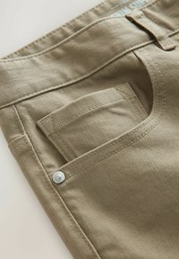 Pantalons khaki avec une poche diagonale, un design à plat, des détails de bouton métalliques et un tissu lisse.