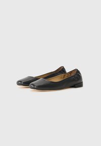 Ballerines noires en cuir avec un bout arrondi, un petit talon et un bord élastiqué pour un enfilage facile. Texture lisse avec des détails de design minimaux.