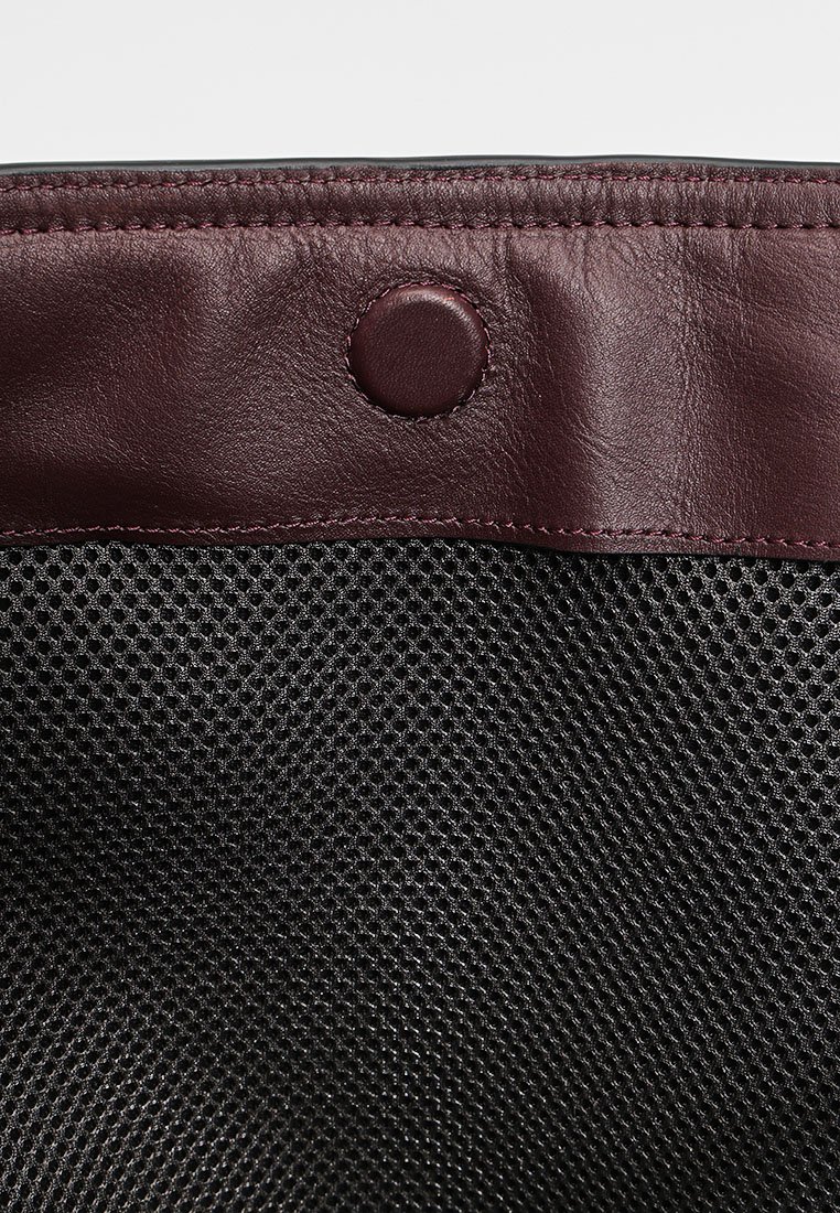 Schwarze Netztasche mit einem bordauxfarbenen Lederbesatz. Verfügt über einen runden Druckverschluss und eine strukturierte Oberfläche des Leders. Funktionales und strukturiertes Design.