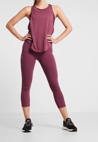 Bordowy sportowy top na ramiączkach w połączeniu z pasującymi legginsami capri. Wykonany z miękkiego, lekkiego materiału o luźnym kroju. W komplecie czarne buty sportowe.