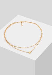 Collana con strati d'oro caratterizzata da catene delicate, piccole perline e un ciondolo a stella. Presenta una chiusura con lunghezza regolabile.