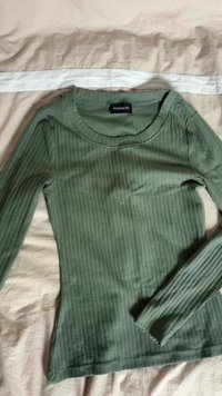 Long-sleeve, ribbed top in muted green. Features a round neckline and fitted design, with smooth texture and subtle sheen.