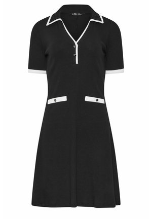 Czarna sukienka z krótkim rękawem z białą lamówką na kołnierzyku, mankietach rękawów, plisie na guziki oraz fałszywych klapkach kieszeni, każda ozdobiona dwoma czarnymi guzikami.