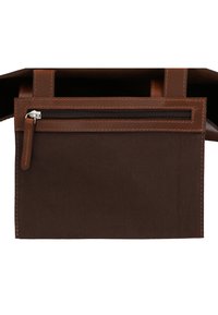 Hnědá plátěná taška s koženým vrškem, se zipovou kapsou a podrobným prošíváním. Design je otevřený nahoře pro snadný přístup.