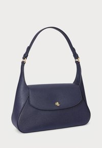 Navy blue handbag made of textured leather with a curved shape, a single adjustable strap, and a gold logo accent on the front.