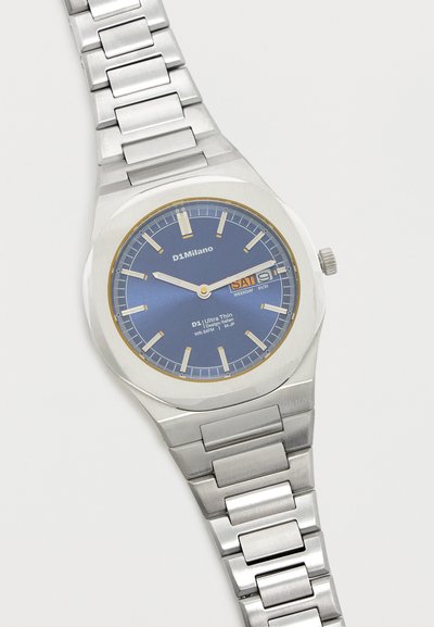 Ασημένιο μεταλλικό ρολόι χειρός με στρογγυλό μπλε καντράν, ένδειξη ημέρας και ημερομηνίας, δείκτες ώρας σε μορφή γραμμής και μεταλλικό μπρασελέ με συνδέσμους.