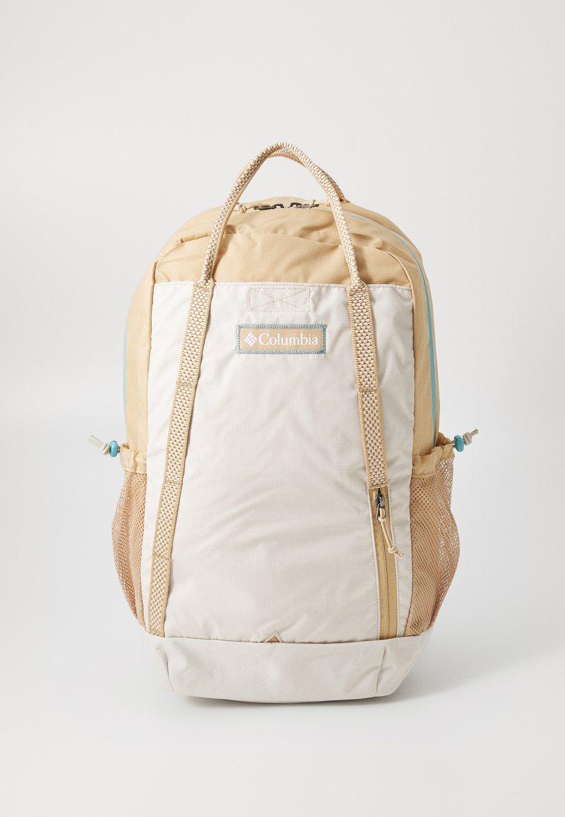 Beige en crèmekleurige rugzak met dubbele schouderbanden, mesh zijzakken en een centrale ritssluiting. Columbia-logo prominent weergegeven aan de voorkant.