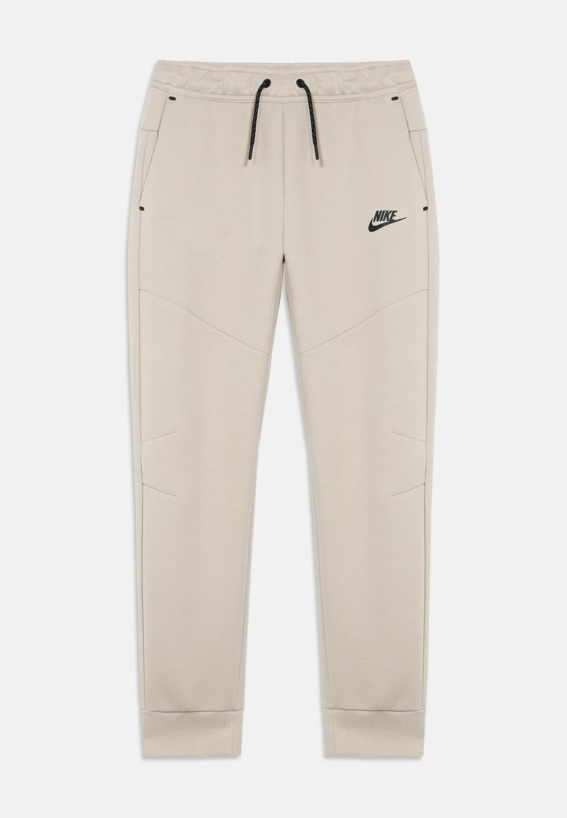 Μπεζ παντελόνι φόρμας με ελαστική μέση και κορδόνι, με πλαϊνές τσέπες, αντίθετες μαύρες λεπτομέρειες και μικρό μαύρο λογότυπο Nike μπροστά.