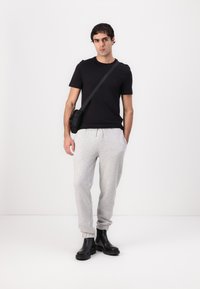 Black short-sleeve t-shirt, gray jogger pants, and black ankle boots. Simple design, casual fit, and light texture in clothing materials.