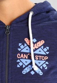 Marineblauwe rits-hoodie met witte trekkoord, voorzien van een kleurrafische afbeelding in roze en lichtblauw met de tekst "CAN'T STOP."