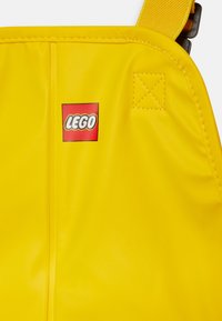 Rumena LEGO torba z logotipom, gladka tekstura in všitki. Zasnovana za trajnost in praktično uporabo.