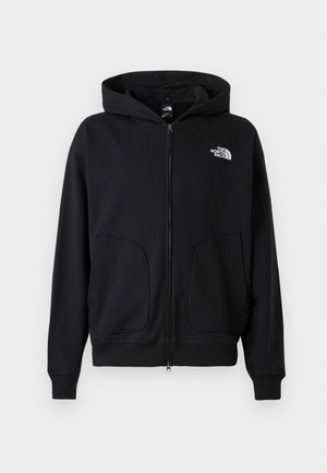 Black zip-up hoodie with a lined hood, side pockets, ribbed cuffs and hem, featuring a white logo on the left chest. Smooth fabric texture.