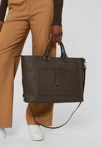 Brun texturerad läderaxelväska med dubbla handtag, ytterficka och avtagbar axelrem. Slät yta med diskret detaljer.