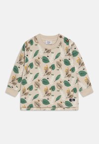 Haut beige à manches longues avec des motifs de feuilles vertes et brunes, comportant des insectes jaunes et un bouton-pression à l'épaule. Tissu en coton doux.