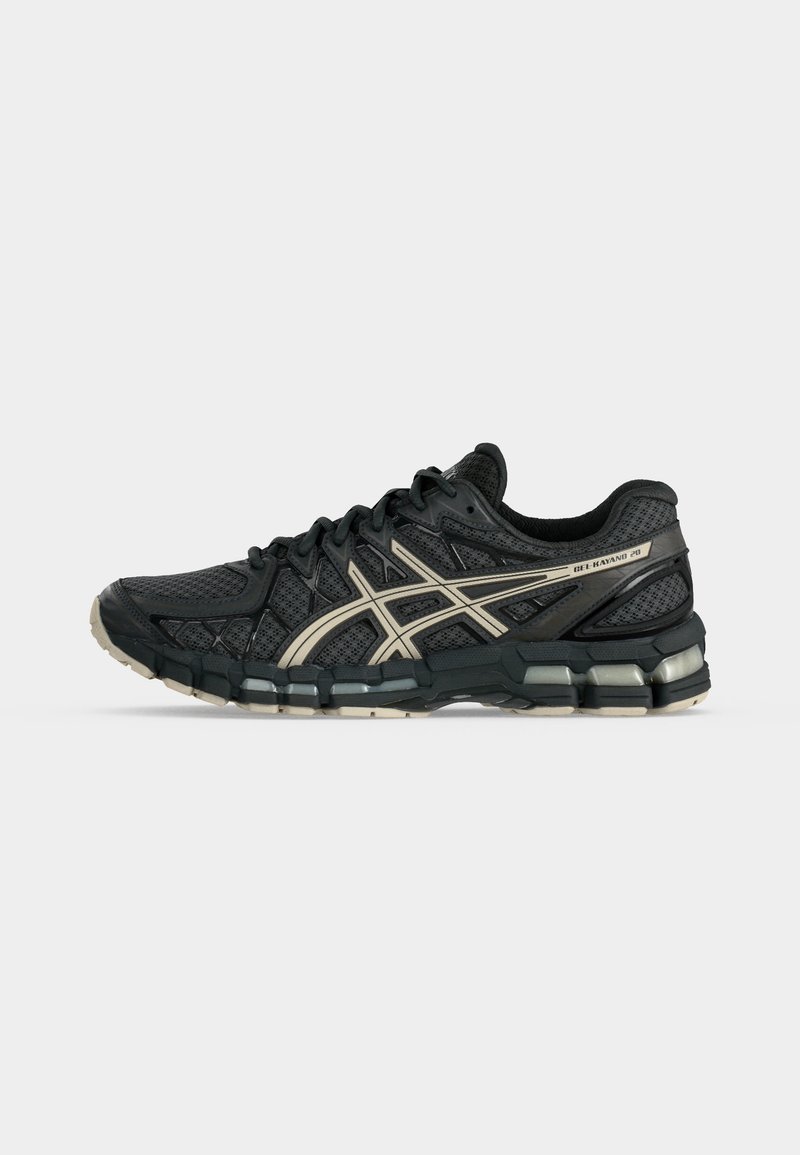 Zapatilla de running Asics Gel-Kayano 28 en negro y gris con parte superior de malla, franjas de logo beige y suela acolchada sobre fondo blanco.