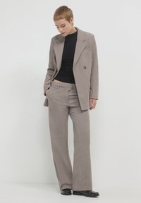 Helles braunes Cordanzug mit weit geschnittenen Hosen und einem passenden übergroßen Blazer. Der Blazer verfügt über einen einzelner Knopf und Revers.