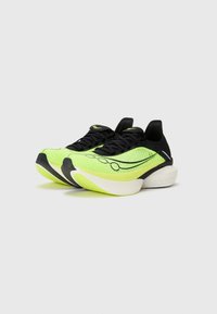 Las zapatillas de correr amarillo neón presentan un upper texturizado, cordones negros, acentos negros y una suela gris claro con un logo distintivo en el costado.