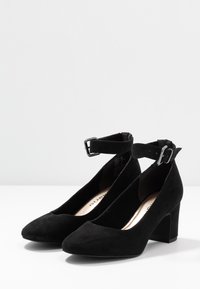 Décolleté nere in suede con tacco alto e punta affusolata, dotate di cinturino alla caviglia regolabile con fibbia in argento. Texture liscia, design classico.